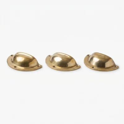 Three polished brass cup-style drawer pulls with mounting holes arranged in a row on a white background.