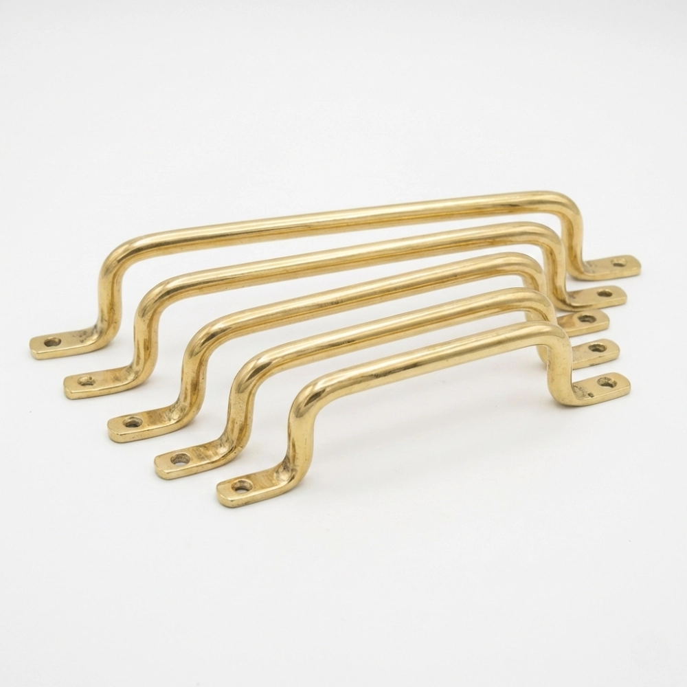 Five brass cabinet pulls in graduated sizes with curved tubular grips and flat mounting tabs with screw holes on white background.