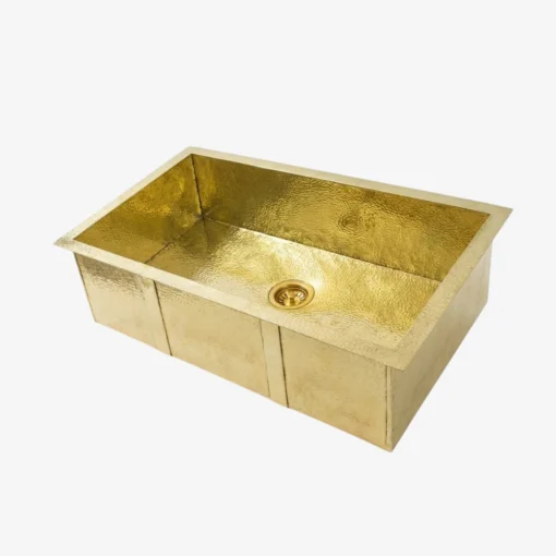 Hammered brass rectangular single-bowl kitchen sink with central drain, shown against a white background
