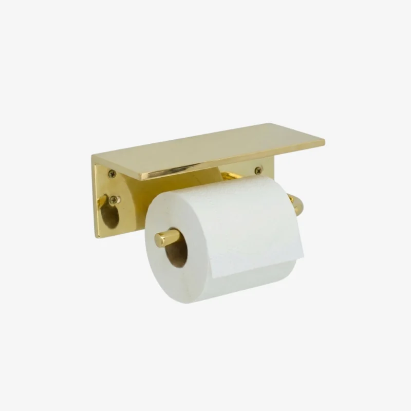 Brass wall-mounted toilet paper holder with a flat rectangular shelf and a white roll on a horizontal spindle.